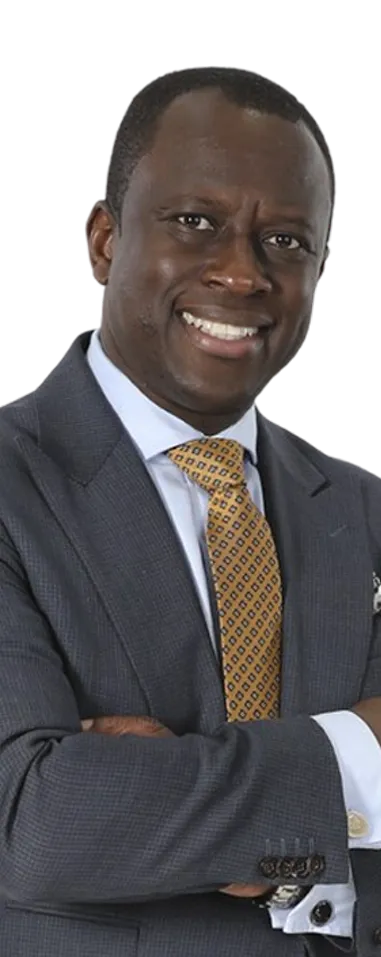 Portrait of a smiling man in a dark suit, white shirt, and patterned yellow tie with arms crossed.