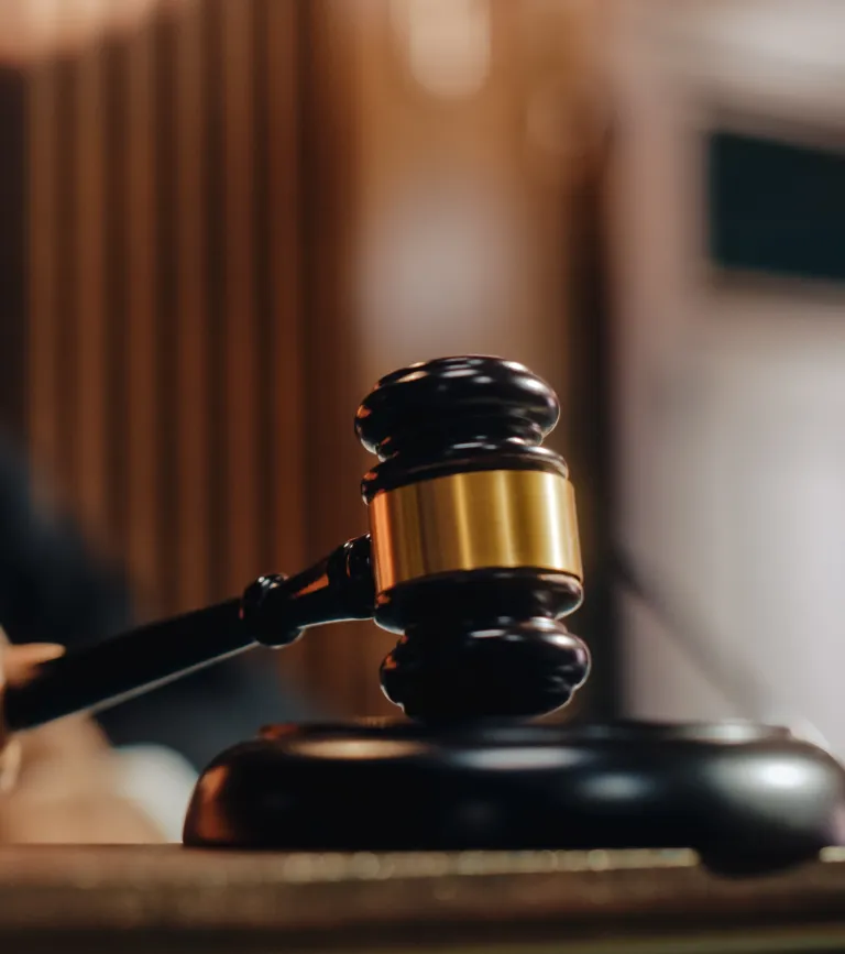 Close-up of a black and gold judge's gavel striking a wooden sound block.