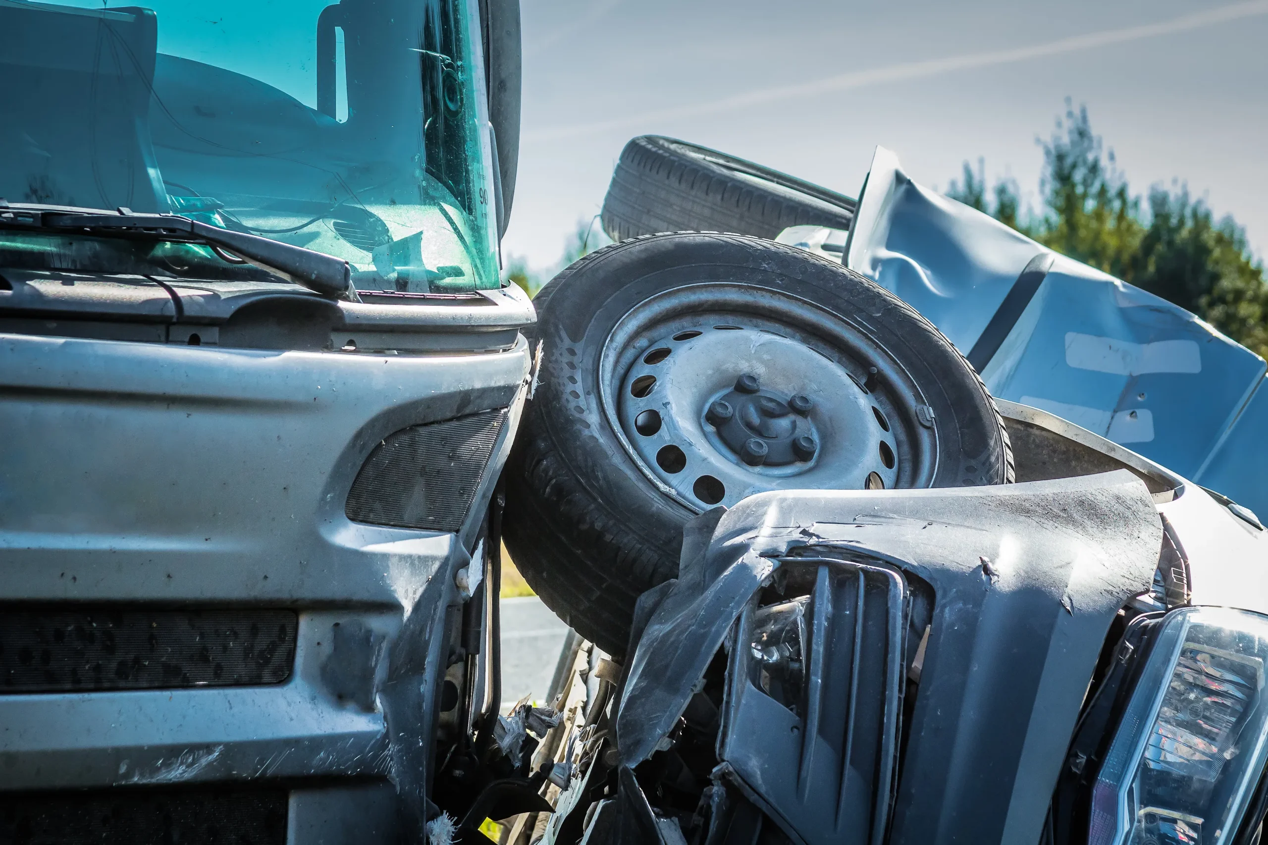 Close-up of a gray truck and a damaged overturned car involved in a collision.